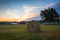 Hay bales rolled on field at sunrise with fog creates amazing sky in early summer Royalty Free Stock Photo