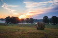 Hay bales rolled on field at sunrise with fog creates amazing sky in early summer Royalty Free Stock Photo