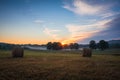 Hay bales rolled on field at sunrise with fog creates amazing sky in early summer Royalty Free Stock Photo