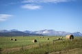 Hay bales scattered across the field with mountains in the background Royalty Free Stock Photo