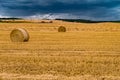 Hay bales under cloudy storm sky on harvested wheat field Royalty Free Stock Photo