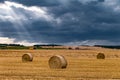 Hay bales under cloudy storm sky on harvested wheat field Royalty Free Stock Photo