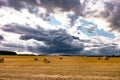 Hay bales under cloudy storm sky on harvested wheat field Royalty Free Stock Photo