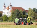 Hay harvest time, the farmer checks the hay bales tractor in front of Schlehdorf Abbey Royalty Free Stock Photo