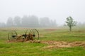 Hay rake in field in fog