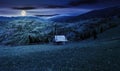 Hay shed on a grassy field in mountains at night Royalty Free Stock Photo