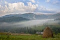 Hay stack on a green meadow in the mountains in the morning Royalty Free Stock Photo