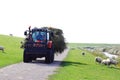Hay transporting tractor along dutch sheep dike, Ameland