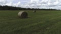 Haystack agriculture field landscape with pine trees growing in the distance against blue cloudy sky. Shot. Hay bales Royalty Free Stock Photo