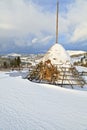 Haystack in thick snow, view of snowcovered mountains, sunny winter day.