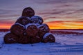 Haystacks in a field folded pyramid at sunset and red yellow sky in winter postcard landscape view Royalty Free Stock Photo