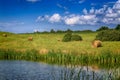 Haystacks on the field with a pond