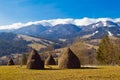 Haystacks on hill slope, farming field in highland area of Carpathian Mountains in Transcarpathia, white clouds on top Royalty Free Stock Photo