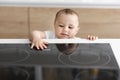 Curious toddler reaching hand to hot electric cooktop Royalty Free Stock Photo