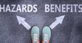 Hazards and benefits as different choices in life - pictured as words Hazards, benefits on a road to symbolize making decision and