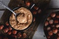 Hazelnut butter in ceramic cup with shelled hazelnuts on wooden background Royalty Free Stock Photo