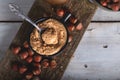 Hazelnut butter in ceramic cup with shelled hazelnuts on wooden background Royalty Free Stock Photo