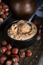 Hazelnut butter in ceramic cup with shelled hazelnuts on wooden background Royalty Free Stock Photo