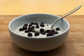 Hazelnut yogurt with chocolate crispies in a white cup on wooden table.