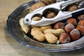 hazelnuts, peanuts and walnuts with a nutcracker on an old silver plate on rustic wood Royalty Free Stock Photo