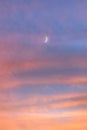 Hazy crescent moon glowing in a vibrant pink sunset sky Royalty Free Stock Photo