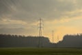 Hazy field and forest with electricity pylons in the flemish countryside Royalty Free Stock Photo