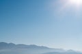 Hazy foggy mountain silhouettes with aerial perspective against a clear blue sky