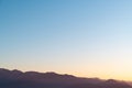 Hazy misty burgundy mountain silhouettes against a blue and yellow sundown sky