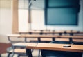 Hazy schoolroom with vacant tables and chairs and no pupils.