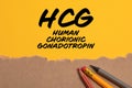 HCG human chorionic gonadotropin. Torn cardboard paper on yellow background