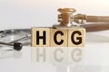 HCG the word on wooden cubes, cubes stand on a reflective white surface, on cubes - a stethoscope