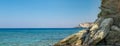 HD wallpaper. Panorama with view a beautiful stone huge cliff and the sea in the background. Stones in the beautiful blue sea.