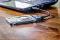 Hdd 2.5 internal hard drive disk connected to laptop via sata usb cable on wooden table closeup view Royalty Free Stock Photo