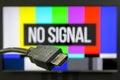 HDMI cable plug in front of tv screen displaying no signal image Royalty Free Stock Photo