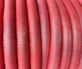 HDPE corrugated pipe texture background. Protection underground cable. Rolled up red corrugated PVC pipe. Red building pipes. Royalty Free Stock Photo