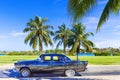 HDR - American black vintage car parked under palms near the beach in Varadero Cuba - Serie Cuba Reportage Royalty Free Stock Photo