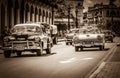 HDR - American Chevrolet classic cars and a Ford Fairlane classic car with white roof drives o