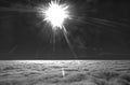 HDR black and white photo of an airplane wing against the blue sky with clouds underneath and brigh shining sun in in front of it Royalty Free Stock Photo