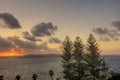 HDR image of a sunset on the horizon behind three trees and a sea Royalty Free Stock Photo