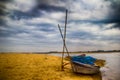 HDR landscape of a boar tied at the corner of river bed sandy beach and cloudy sky day time scene. Royalty Free Stock Photo