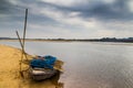 HDR landscape of a boar tied at the corner of river bed sandy beach and cloudy sky day time scene. Royalty Free Stock Photo