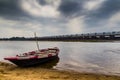 HDR landscape of a boar tied at the corner of river bed sandy beach and cloudy sky day time scene. Royalty Free Stock Photo