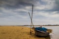 HDR landscape of a boar tied at the corner of river bed sandy beach and cloudy sky day time scene. Royalty Free Stock Photo