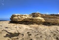 HDR panorama photo of a sunny day at the sea coast with deep blue clean water and a nice stone beach and a large rock on the right