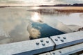 HDR photo of melt water behind metallic bridge railings at a freezing lake