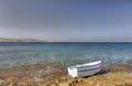 HDR photo of a sunny day at the sea coast with deep blue clean water and a nice stone beach and a small white boat in front Royalty Free Stock Photo