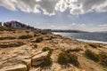 HDR photo of a sunny day at the sea coast with deep blue clean water and a nice stone beach and vegetation growing there Royalty Free Stock Photo