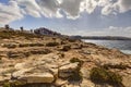 HDR photo of a sunny day at the sea coast with deep blue clean water and a nice stone beach and vegetation growing there Royalty Free Stock Photo