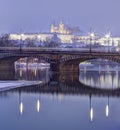 HDR winter photo of a bridge across Vltava river reflecting on the water surface and the Prague castle in the background Royalty Free Stock Photo