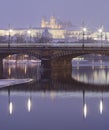 HDR winter photo of a bridge across Vltava river reflecting on the water surface and the Prague castle in the background Royalty Free Stock Photo